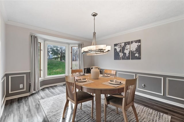 dining space with crown molding, wainscoting, wood finished floors, and a chandelier