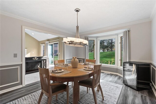 dining space with a healthy amount of sunlight, crown molding, dark wood-style floors, and a notable chandelier