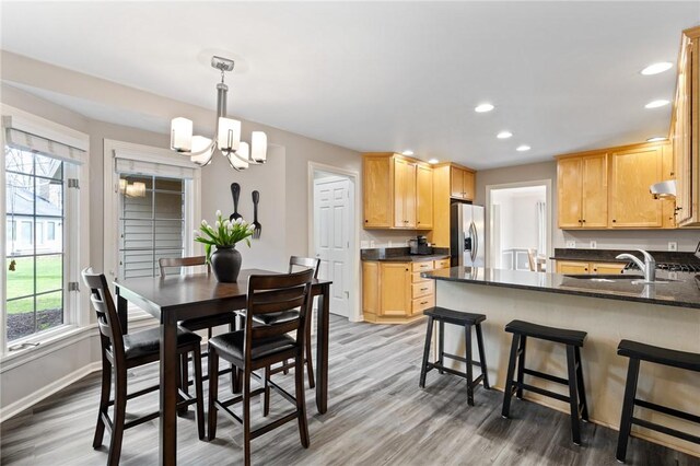 dining area featuring recessed lighting, baseboards, a notable chandelier, and light wood-style flooring