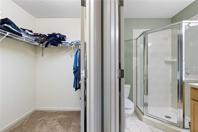 full bathroom featuring vanity, a walk in closet, a stall shower, and toilet