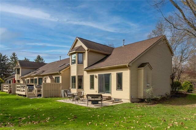 back of property with a lawn, a shingled roof, a patio area, and a wooden deck