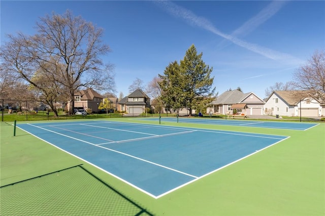 view of tennis court featuring community basketball court, fence, and a residential view