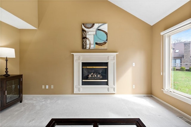 unfurnished living room with visible vents, a glass covered fireplace, lofted ceiling, baseboards, and carpet flooring