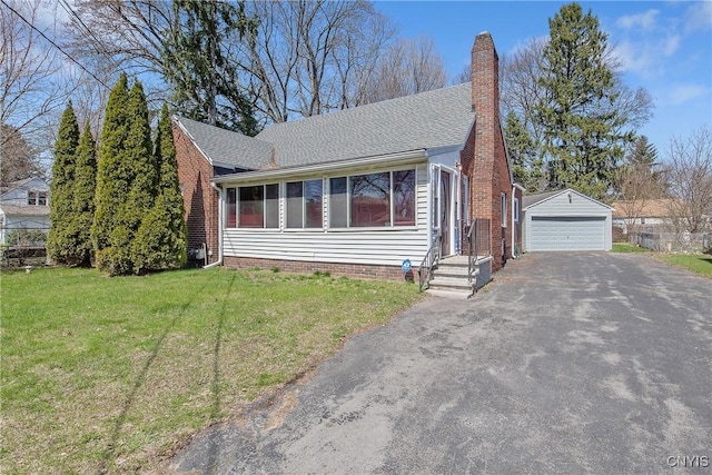 view of front of property featuring a shingled roof, a garage, a front yard, a chimney, and an outdoor structure