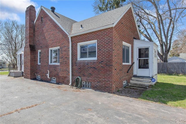 back of house with brick siding, a chimney, and entry steps