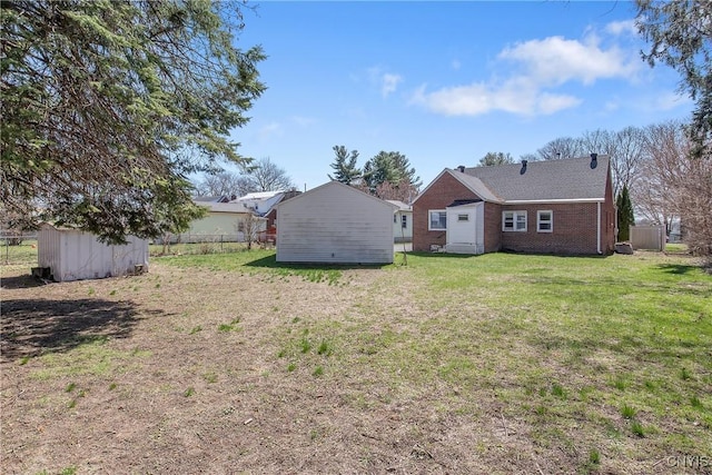 back of house with a lawn, an outbuilding, brick siding, fence, and a storage unit