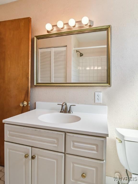 bathroom featuring toilet, walk in shower, and vanity