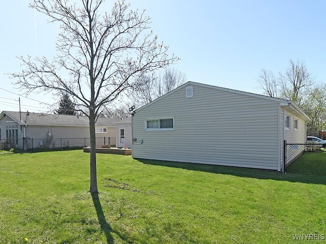 view of side of property featuring fence and a lawn