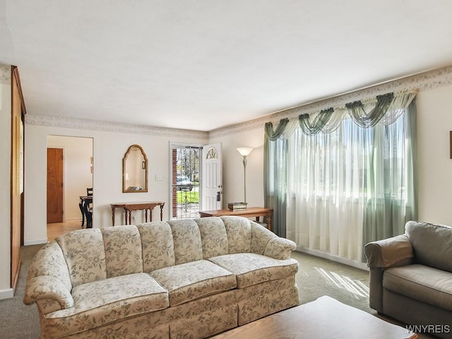 living area with baseboards and light colored carpet