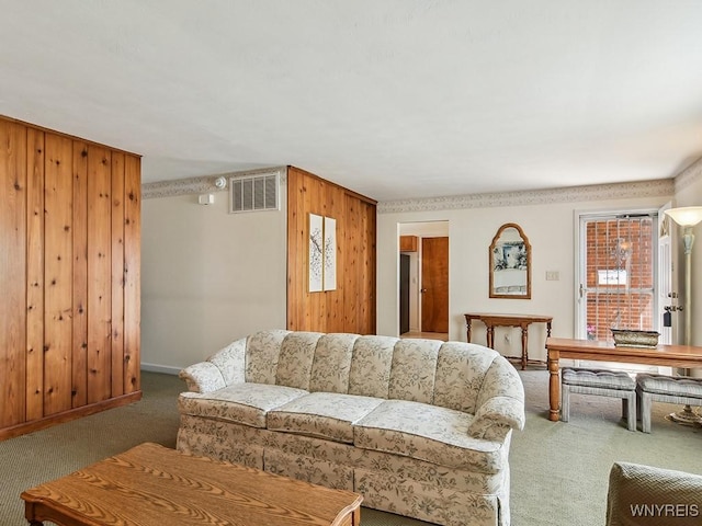 carpeted living area featuring wood walls, visible vents, and baseboards
