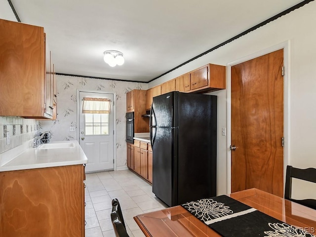 kitchen with brown cabinets, a sink, light countertops, black appliances, and light tile patterned flooring