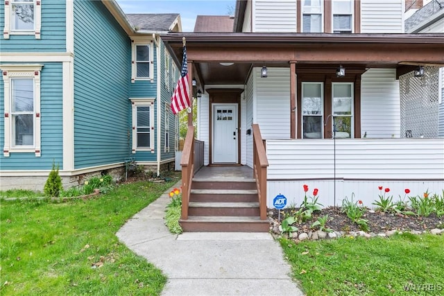 entrance to property featuring covered porch and a yard