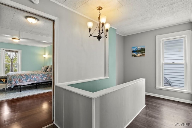 hall featuring baseboards, dark wood finished floors, and a chandelier