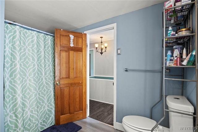 bathroom with toilet, wood finished floors, and a notable chandelier