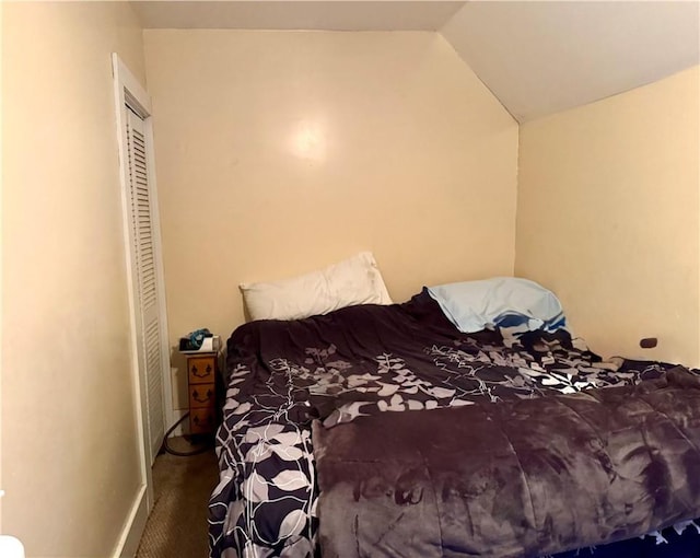 bedroom featuring a closet, baseboards, vaulted ceiling, and carpet flooring