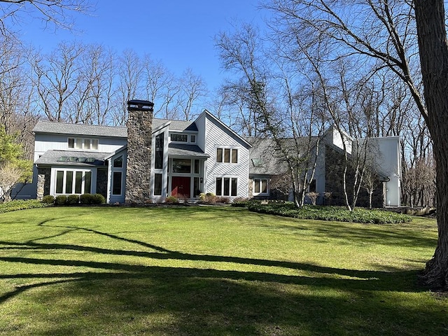 rear view of property with a chimney and a yard