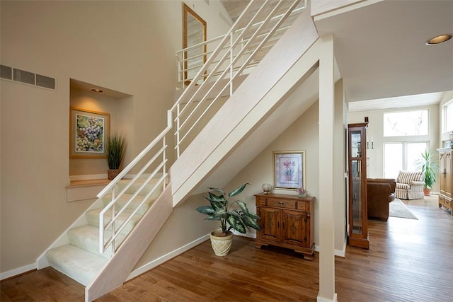 stairway with visible vents, baseboards, and wood finished floors
