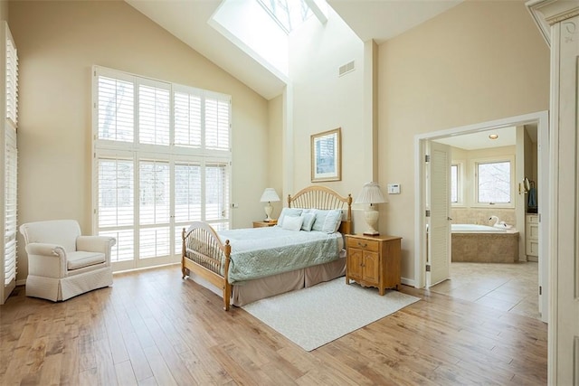 bedroom featuring visible vents, light wood-style floors, baseboards, high vaulted ceiling, and a skylight
