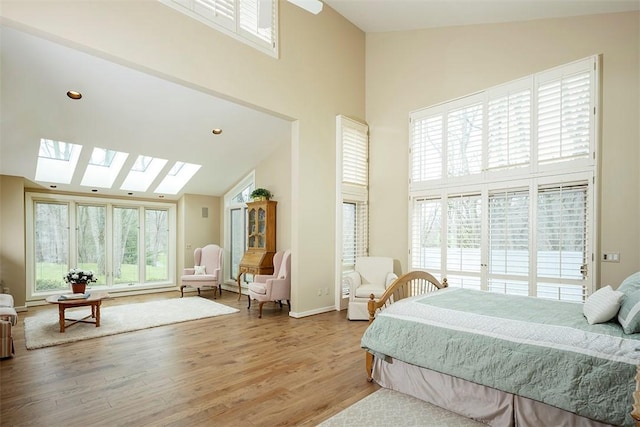 bedroom featuring a skylight, multiple windows, wood finished floors, and high vaulted ceiling