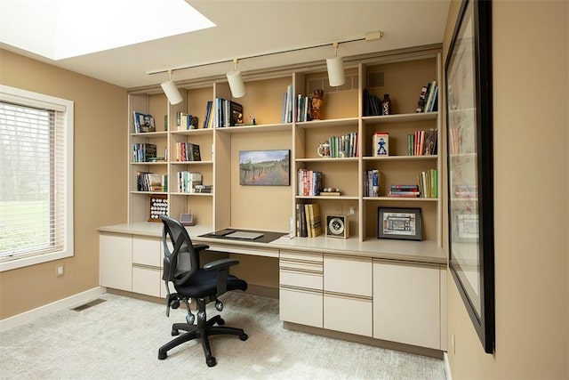 home office with track lighting, visible vents, built in study area, baseboards, and light colored carpet