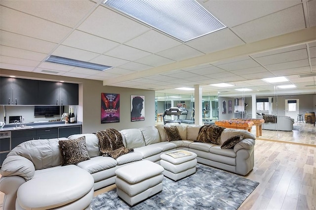 living area with light wood-style flooring and a drop ceiling