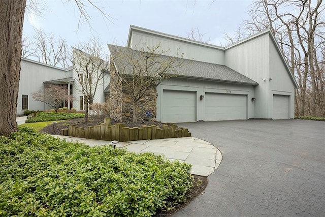view of front of property with roof with shingles, an attached garage, and driveway