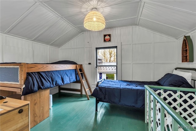 bedroom featuring vaulted ceiling, wood finished floors, and a decorative wall