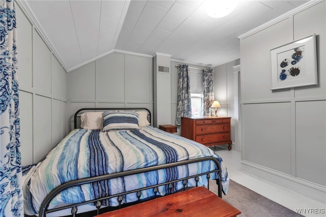 carpeted bedroom with crown molding, vaulted ceiling, visible vents, and a decorative wall
