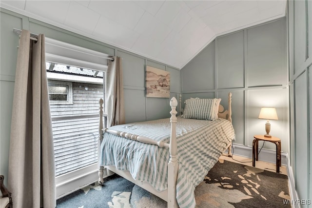bedroom featuring lofted ceiling and a decorative wall