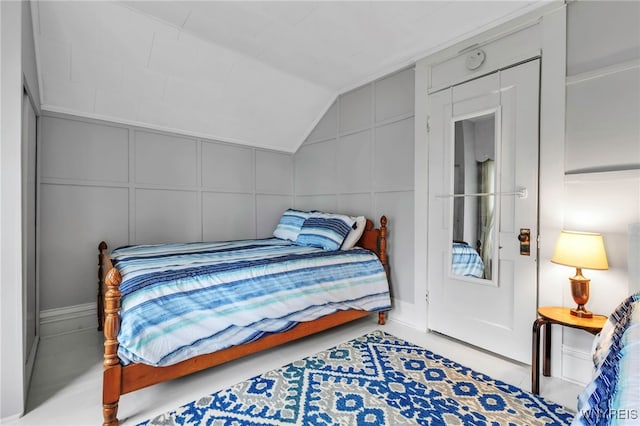 bedroom featuring vaulted ceiling and a decorative wall