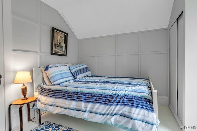 bedroom with a decorative wall and lofted ceiling
