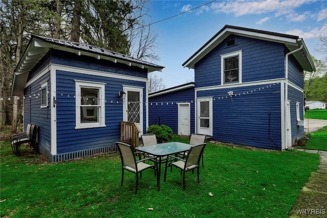rear view of property featuring a lawn and outdoor dining area