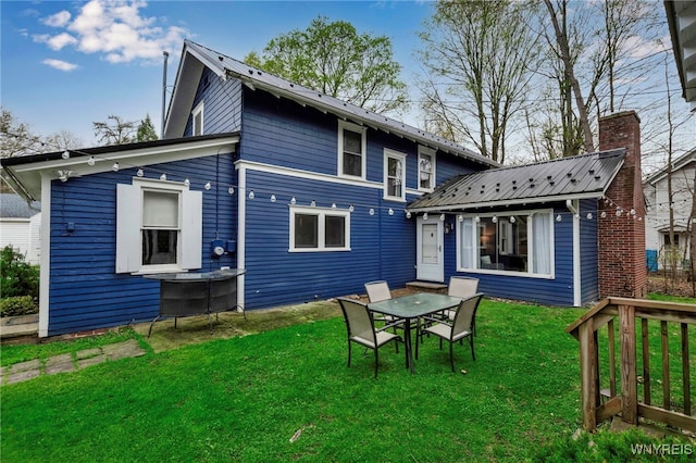 back of property with a lawn, an outbuilding, and metal roof
