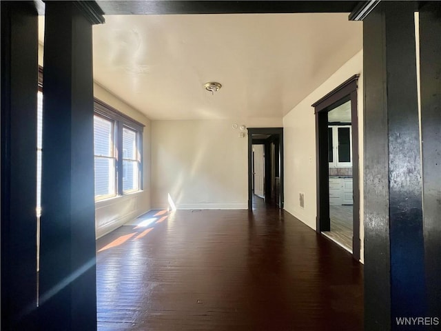spare room with baseboards and wood finished floors