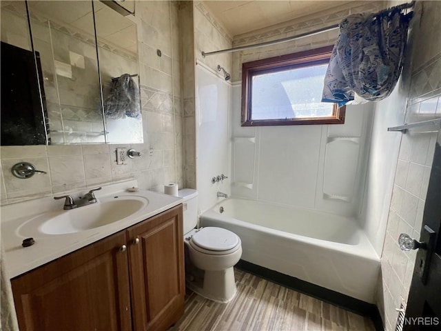 bathroom featuring washtub / shower combination, vanity, toilet, tile walls, and wood finished floors