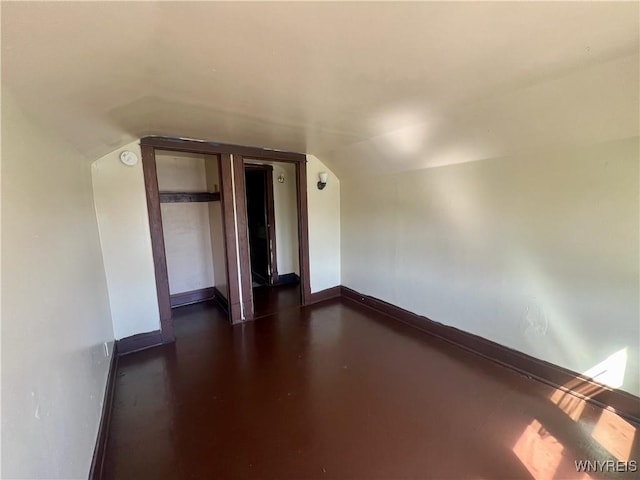 additional living space with baseboards and vaulted ceiling