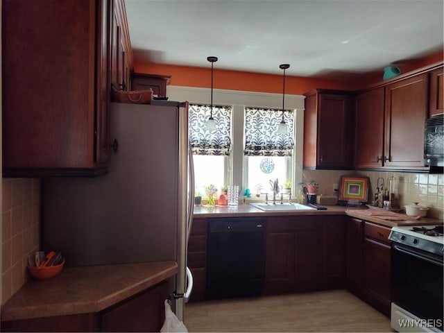 kitchen with a sink, light countertops, tasteful backsplash, pendant lighting, and black appliances