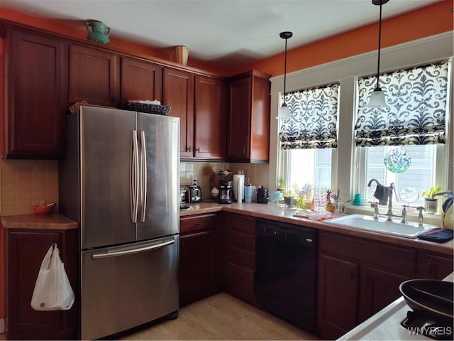 kitchen featuring decorative backsplash, dishwasher, a sink, light countertops, and freestanding refrigerator