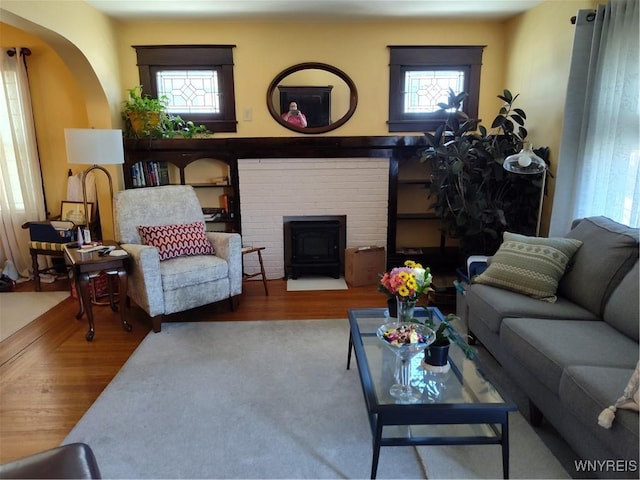 living room featuring arched walkways, plenty of natural light, and wood finished floors