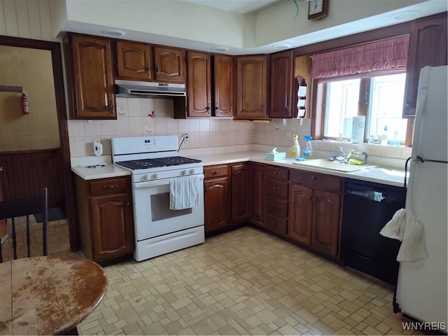 kitchen with light countertops, backsplash, under cabinet range hood, and white appliances
