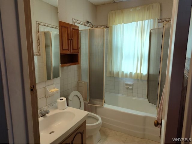 bathroom featuring vanity, bathing tub / shower combination, toilet, and tile walls