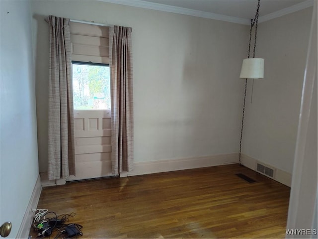 empty room with crown molding, wood finished floors, and visible vents