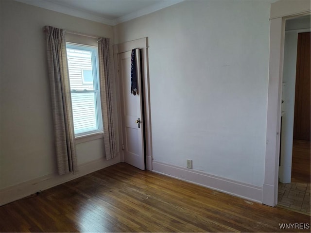 spare room featuring crown molding, baseboards, a wealth of natural light, and wood finished floors