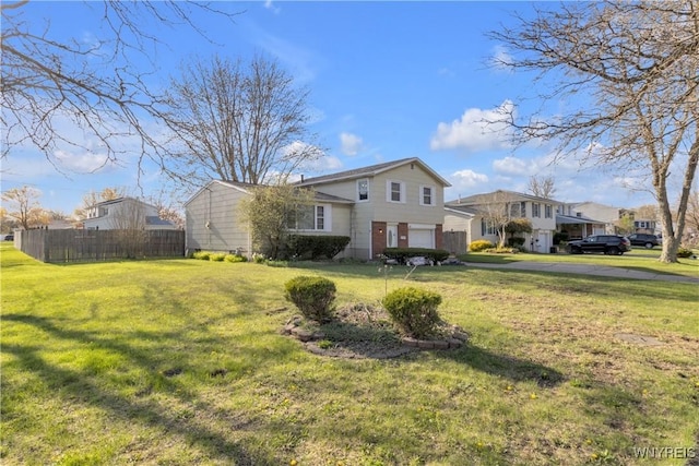 view of front facade featuring an attached garage, fence, driveway, and a front yard