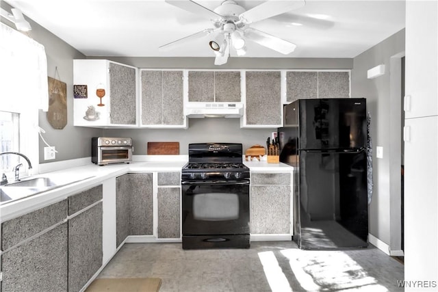 kitchen with a ceiling fan, light countertops, under cabinet range hood, a sink, and black appliances