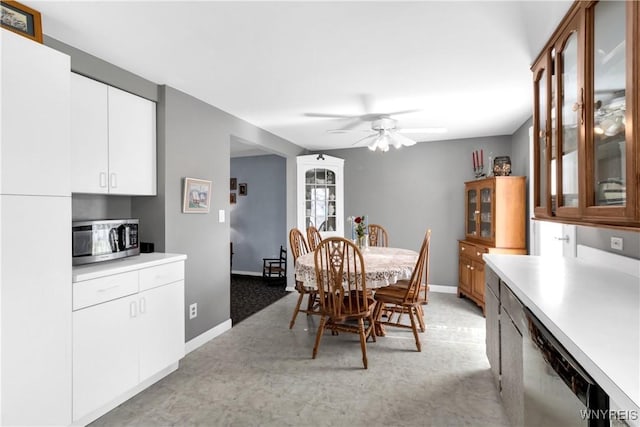 dining space featuring baseboards, ceiling fan, and light colored carpet