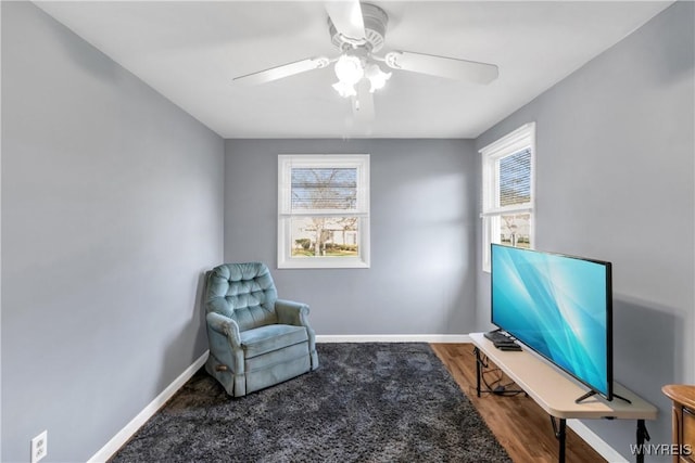 living area featuring plenty of natural light, baseboards, ceiling fan, and wood finished floors