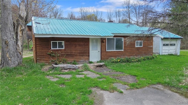 view of front of home featuring a chimney, metal roof, a front yard, and a garage