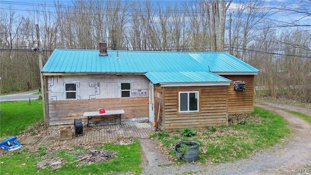 rear view of property featuring a chimney and metal roof