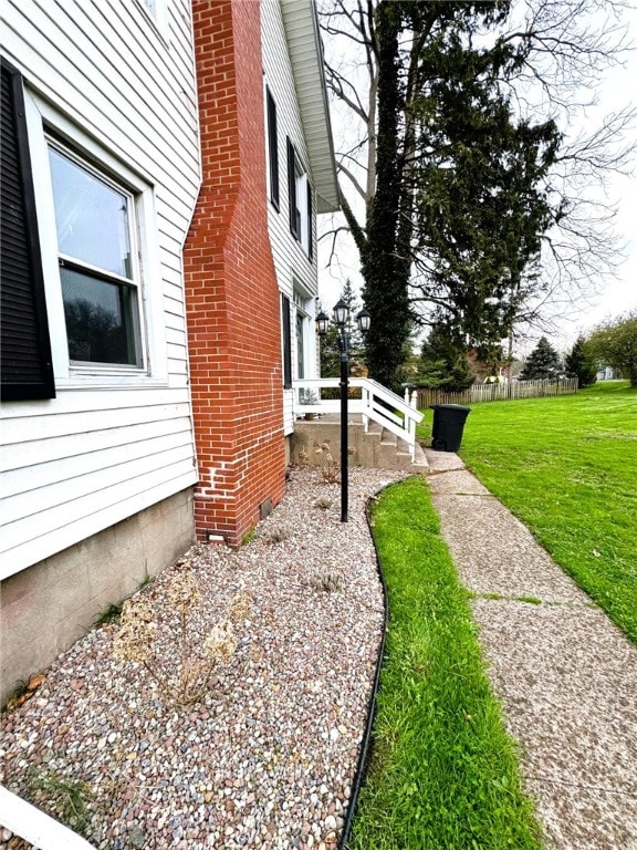 view of side of home featuring a lawn, crawl space, and fence